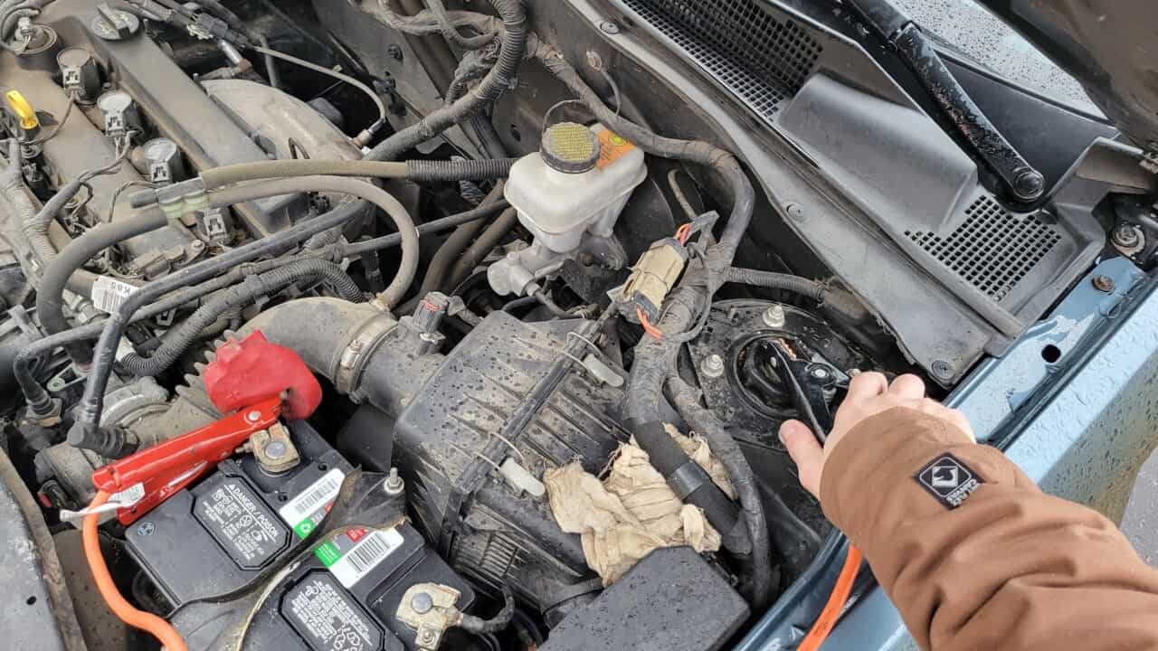 image showing how to hook the negative jumper cable to the car's chassis so that you don't create a dangerous spark above the battery vents.